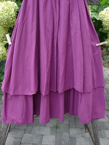 Barclay NWT Batiste Fold Over Stardust Tier Skirt Tyrian Berry Size 0, displayed clipped on a wooden frame, showcasing its rich layers and generous A-line tiers against a backdrop of greenery.