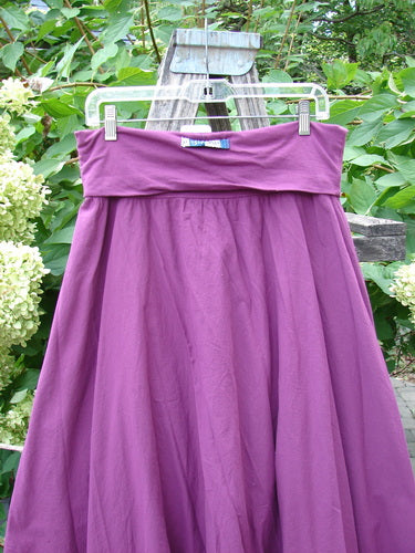 Barclay NWT Batiste Fold Over Stardust Tier Skirt Tyrian Berry Size 0, showcasing a flowy, tiered design with a fold-over waistband, draped on a hanger against a lush outdoor setting.