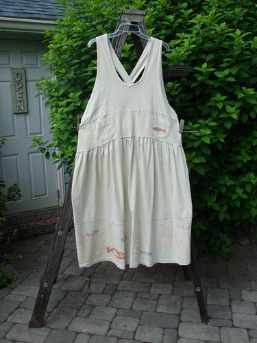 1999 NWT Tadpole Jumper Single Orange Pike Natural OSFA hanging on a clothesline, showcasing its adjustable shoulder straps, sweeping hemline, and crisscross lower back, highlighting the organic cotton fabric.