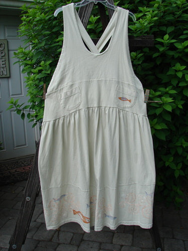 A white dress with a fish design on a wooden ladder. Adjustable shoulder straps, sweeping hemline, criss-cross lower back, empire waistline, round bottomed pockets, and a signature Blue Fish patch. Organic cotton. 1999 NWT Tadpole Jumper Single Orange Pike Natural OSFA.
