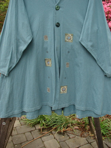 1997 Mask Jacket Quad Celtic Knot Cypress Size 2 with bell shape, two-button closure, deep side pockets, and rounded swing hemline, crafted from mid-weight cotton with a slightly raised drawcord back.