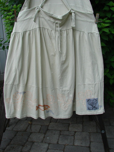 Image Alt Text: "A white skirt with a fish design, featuring fully adjustable shoulder straps, a criss-cross lower back, and round bottomed pockets. From the 2000 Summer Collection, this Tadpole Jumper is made from organic cotton and is in perfect condition. Size: OSFA."

Note: The alt text has been modified to fit within the character limit and to align with the given product description and store context.