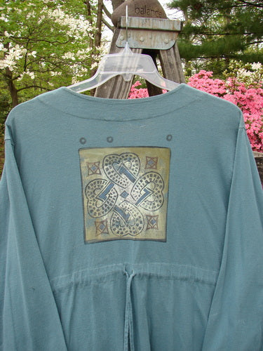 1997 Mask Jacket Quad Celtic Knot Cypress Size 2, featuring a bell shape, two special button closures, deep side pockets, a varying rounded hemline, and a slightly raised drawcord back.