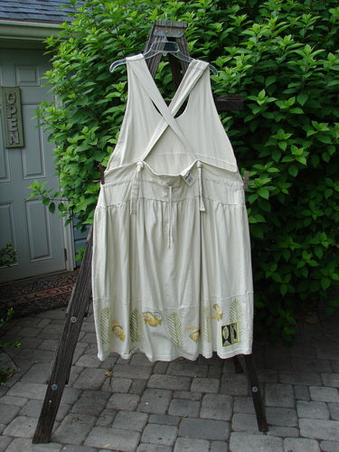1999 NWT Tadpole Jumper Single Gold Fish Dawn Natural OSFA displayed on a wooden rack with adjustable shoulder straps, sweeping hemline, crisscross back, round pockets, and signature Blue Fish patch.