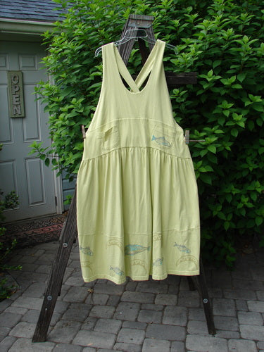 1999 NWT Tadpole Jumper Single Bass Moon Natural Citron OSFA: Yellow dress with adjustable straps, sweeping hemline, criss-cross back, and unique fish pattern on a wooden rack.