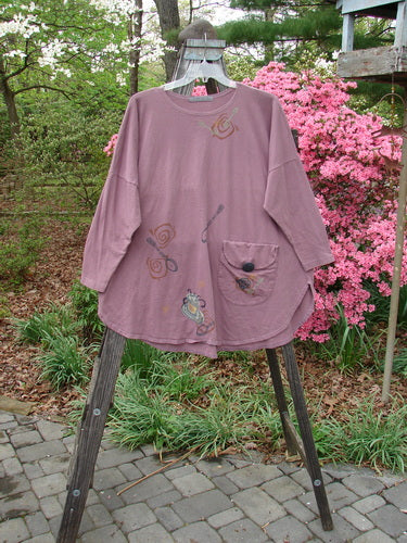 1996 Long Sleeved Pop Top Tea Time Laurel OSFA on a hanger, featuring a rounded hemline, scooped rolled neckline, oversized front pocket with textured button, and rear drawcord back.