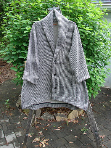 Barclay Patched Wool City Side Big Pocket Coat features black and white stripe herringbone, a stand-up collar, sectional panels, triple button closure, deep front pockets, and an A-line flair, highlighting its unique design.