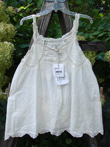 Magnolia Pearl NWT Embroidered Eyelet Cotton Clementine Tank True OSFA drapes on a hanger, showcasing lace details, pintucks, and eyelet panels over a wooden trellis, embodying vintage charm.