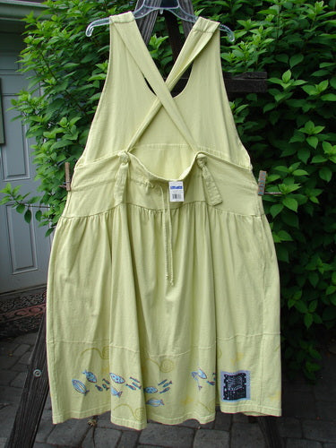 A yellow dress with adjustable shoulder straps, a sweeping hemline, and a criss-cross lower back. Features a double-paneled waistline, round-bottomed pockets, and a single stripe pike and school theme paint around the hem. From the 2000 Summer Collection, this New With Tag Tadpole Jumper is made from organic cotton.