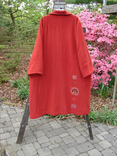 1999 Patched Woven Overcoat Tomato Altered Size 0 displayed on a rack, highlighting its vintage-inspired design with hand-blocked patches, oversized buttons, deep inseam pockets, and a swinging A-line shape.