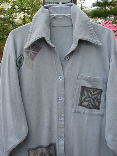 1994 Reprocessed Work Shirt Topiary Moon Solstice Blue OSFA: A grey shirt with a star patch, pointed collar, deep drop shoulders, rounded shirttail, and painted front pocket.