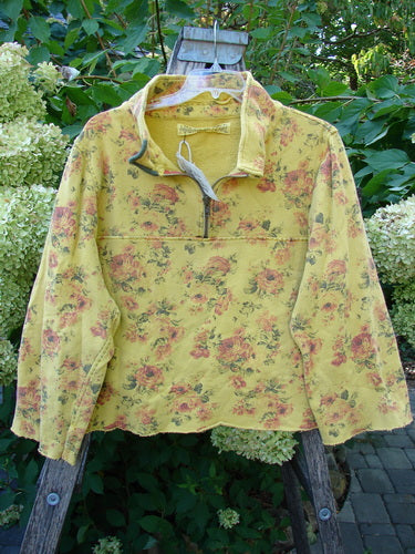 Magnolia Pearl NWT Cotton Fleece Asher Pullover Sweatshirt Vintage Rose Sunnies OSFA hanging on a wooden ladder outdoors, showcasing its soft yellow fabric adorned with pink and red roses, embodying vintage charm.