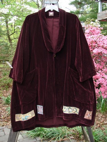 1999 Patched Velveteen Poet's Coat Holiday Deep Burgundy Size 1 displayed on a swing, showcasing its oversized vintage button closures, folded collar, and colorful patches.