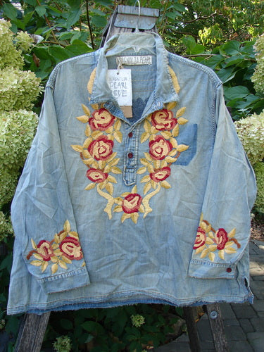 Magnolia Pearl NWT Embroidered Denim Isabel Shirt Washed Indigo OSFA features intricate yellow-gold and deep-red rose embroidery on the collar and cuffs, hanging outdoors, encapsulating BlueFishFinder's vintage and expressive aesthetic.