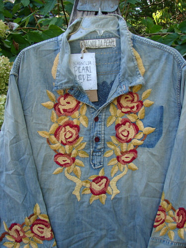 Magnolia Pearl NWT Embroidered Denim Isabel Shirt Washed Indigo OSFA features intricate red and yellow rose embroidery on a light-blue denim-style blouse, with a Henley button front and long cuffed sleeves.