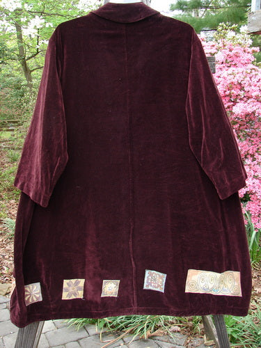 1999 Patched Velveteen Poet's Coat Holiday Deep Burgundy Size 1, featuring colorful patchwork, oversized buttons, floppy pockets, and a folded collar, displayed on a hanger.