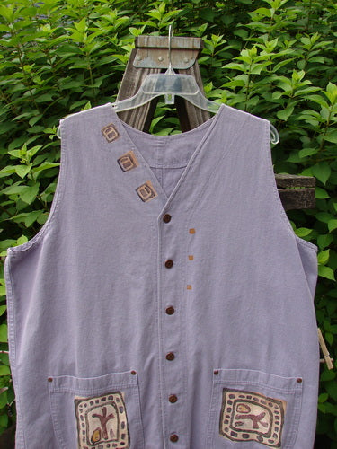 1996 Denim Visionary Vest Travel Stone Stratus Size 1: Light-weight denim vest with V-neckline, metal front buttons, rivet-topped pockets, rear buckle draw tab, and unique artistic paint theme, displayed on a wooden hanger.