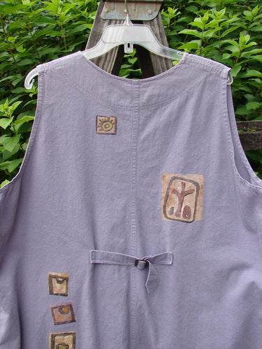1996 Denim Visionary Vest Travel Stone Stratus Size 1, displayed on a hanger, features a V-shaped neckline, metal buttons, rivet-topped pockets, rear buckle draw tab, and artistic travel-themed designs.