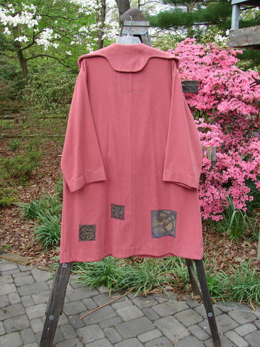 2000 Patched Wool Nora Coat Pastel Geranium Size 0 displayed on a wooden stand, featuring scalloped lines, oversized buttons, and unique patches.