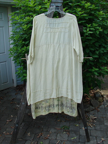 Barclay Hemp Silk Triangular Two Tier Dress, Star Wind Citron, Size 2, features a unique V-shaped neckline, three-quarter sleeves, and a varying hemline, displayed elegantly on a clothes rack.
