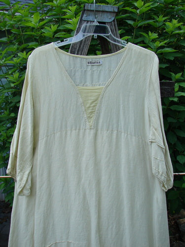 Barclay Hemp Silk Triangular Two Tier Dress in Star Wind Citron shown on a clothes rack, highlighting its two-tier design, V-shaped neckline, and three-quarter sleeves, embodying vintage Blue Fish creativity and individuality.