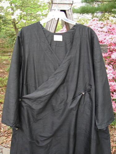 2000 Shaunting Silk Slant Wrap Jacket Unpainted Deep Black Size 2, featuring a kimono-inspired wrap style with wide sleeves and a slanted rear seam, displayed outdoors against lush greenery.