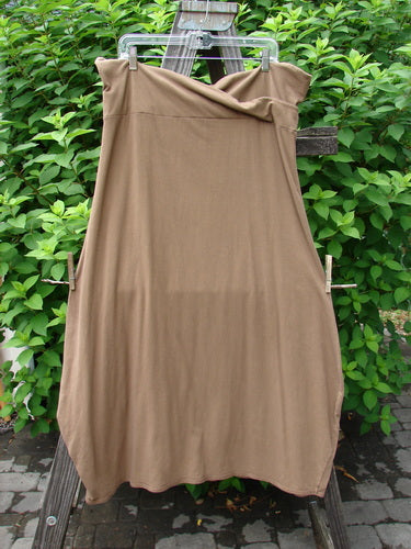 Barclay Cotton Lycra Fold Over Bottom Bell Skirt Unpainted Coco Size 2 hanging on a clothesline, showcasing its cross over front banded waistline and lower bell accent.