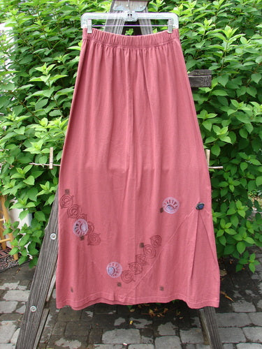 1996 Dubuffet Skirt Tumble Stone Ember Size 2 hanging on a clothesline, showcasing its A-line shape, unique pleated triangular side panels, and painted cloth-covered buttons, part of the Fall Collection.