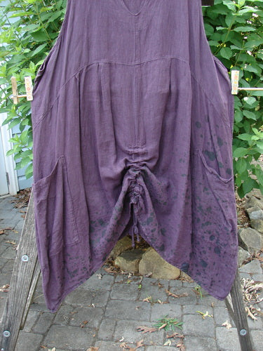 Barclay Linen Two Pocket Pull Up Jumper in Berry Vine Red Plum Size 2, showcasing vertical seams, V neckline, A-line shape, and double pockets, draped beautifully on a clothesline.