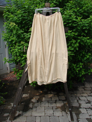 Barclay Gauze Tool Skirt Unpainted Kauiclla Size 2 displayed on a clothes rack outdoors, featuring a full drawcord waistline, widening shape, and gathered fall with vertical tabs accented in hand-dyed silk ribbon.