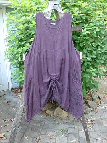 Barclay Linen Two Pocket Pull Up Jumper Berry Vine Red Plum Size 2 hangs gracefully on a clothesline, showcasing its A-line shape, softly dipped V-neckline, and double drop exterior pockets.