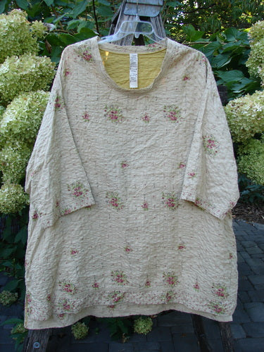 Magnolia Pearl European Cotton Quilted Hi Low Frances Top Vintage Rose OSFA features a loose cut, floral embroidery, scoop neckline, elbow-length sleeves, and a flared hem, displayed outdoors against hydrangeas.