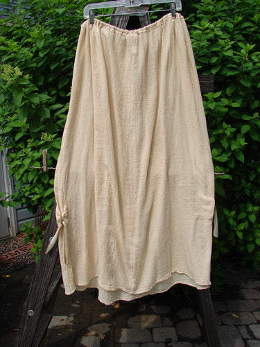 Barclay Gauze Tool Skirt Unpainted Kauiclla Size 2 displayed on a clothes rack, showcasing its full drawcord waistline, widening shape, and gathered fall with vertical tabs accented in hand-dyed silk ribbon.