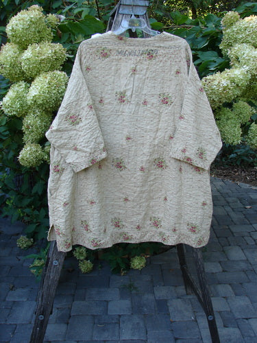 Magnolia Pearl European Cotton Quilted Hi Low Frances Top Vintage Rose OSFA draped on a wooden ladder, showcasing its quilted texture, pink-rose clusters, and unique high-low hemline against a garden backdrop.