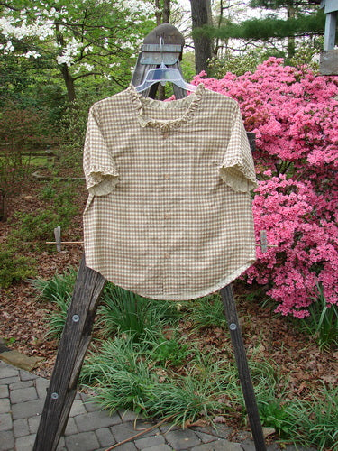1996 Woven Boardwalk Top Unpainted White Pine Gingham Size 2 displayed on a wooden ladder, featuring gathered ruffle neck and sleeve lines, rounded hem, and bust line darts.