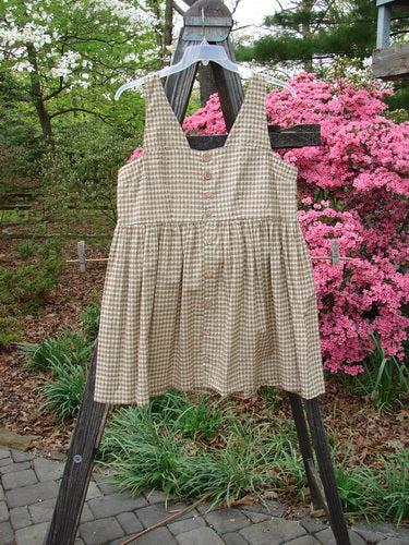 1996 Woven Roadside Jumper in Unpainted White Pine Gingham, displayed on an outdoor clothes rack, featuring wooden buttons, pleated skirt, and square neckline, from BlueFishFinder's Summer Collection.