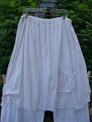 Barclay Gauze Batiste Single Pocket Pant Skirt Unpainted Pink Cloud Size 2 hanging on a clothesline, showcasing its flowing gauze overlay, round bottom pocket, and billowy lower batiste flare.
