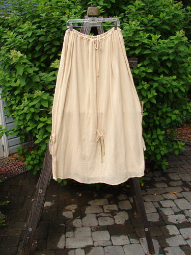 Barclay Gauze Tool Skirt Unpainted Kauiclla Size 2 on a rack, featuring a full drawcord waistline, widening shape, and gathered fall with vertical hand-dyed silk ribbon accents.