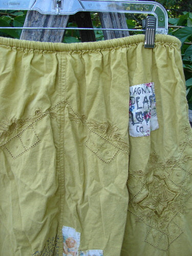 Magnolia Pearl NWT Embroidered Khloe Bloomer Golden Daffodil OSFA hangs on a clear hanger, showcasing intricate diamond and floral eyelet embroidery, with a partially visible MAGNA PEARL CO. patch appliqué.