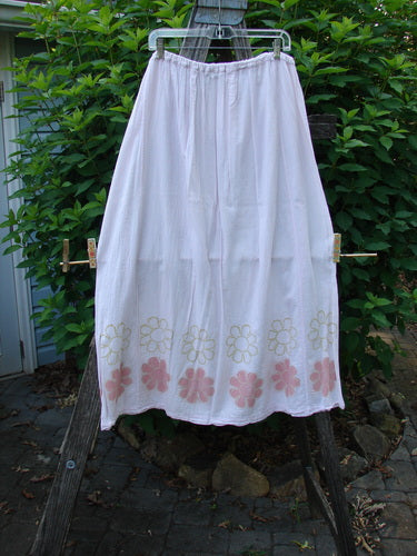 Barclay Batiste Over Skirt Daisy Border Pink Cloud Size 2 features a white skirt adorned with pink floral patterns, showcasing an A-line shape and elastic waistband with tie strings, reflecting BlueFishFinder's vintage style.