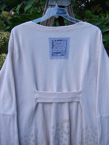 1997 Thermal Voyage Roadside Jacket Windy Floral Shell OSFA features a ribbed upper body, long sleeves, and a gathered skirt with faint circular motifs, hanging outdoors against greenery.