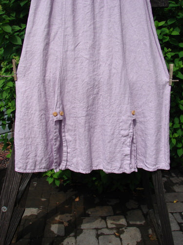 Barclay Linen Double Button Back Vent Skirt Unpainted Pink Cloud Size 2, displayed on a clothesline, showcasing its full elastic waistline and unique front double button vents.