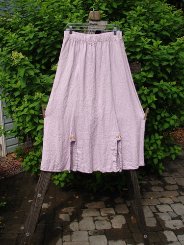 Barclay Linen Double Button Back Vent Skirt Unpainted Pink Cloud Size 2 displayed on a wooden stand, showcasing its full elastic waistline, front double button vents, and rear kick vent.