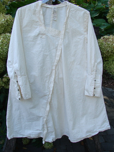 Magnolia Pearl Cotton Poplin Wabi Diagonal Tunic Natural OSFA, displayed on a hanger, features a square neckline, long sleeves with snaps, unique diagonal seams, and a flared open-front profile, embodying creative individuality.