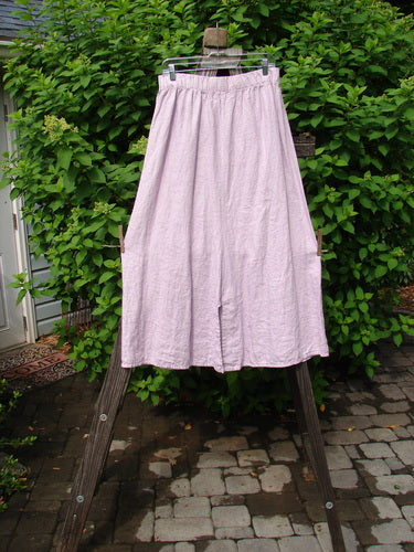Barclay Linen Double Button Back Vent Skirt Unpainted Pink Cloud Size 2, displayed on a clothes rack, showcasing its full elastic waistline, lower widening shape, and unique front double button vents.
