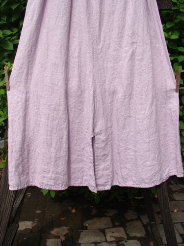 Barclay Linen Double Button Back Vent Skirt Unpainted Pink Cloud Size 2 displayed on a clothes rack, showcasing its full elastic waistline, unique front double button vents, and rear kick vent.