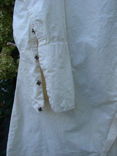 Magnolia Pearl Cotton Poplin Wabi Diagonal Tunic Natural OSFA hangs outdoors, showcasing long sleeves with star-shaped snaps, a crinkled texture, and distinct diagonal seams, embodying creative freedom and individuality.