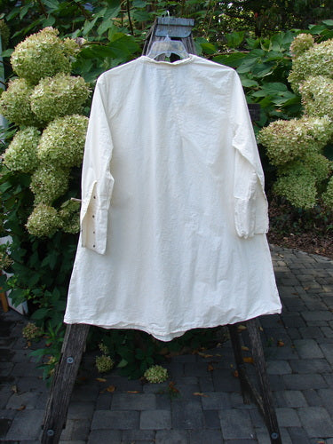 Magnolia Pearl Cotton Poplin Wabi Diagonal Tunic Natural OSFA draped on a ladder, showcasing long sleeves with tiny snaps, diagonal seams, and textured overlays, embodying Bluefishfinder.com's vintage, expressive style.