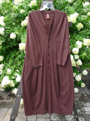 1998 Merino Pria Dress Unpainted Raisin Size 1, displayed on a wooden rack with a unique hourglass shape, ribbed round neckline, and shiny diamond-cut buttons.