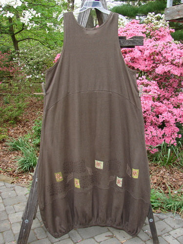 2000 Cotton Hemp Libby Jumper Leaf Flower Bark Size 2 hanging on a clothesline, showcasing a scooped waistline, side pockets, bubbled shape, and leaf and flower theme paint with an elastic hemline.